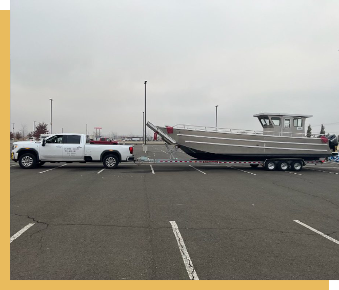 A truck pulling a boat in the back of a trailer.