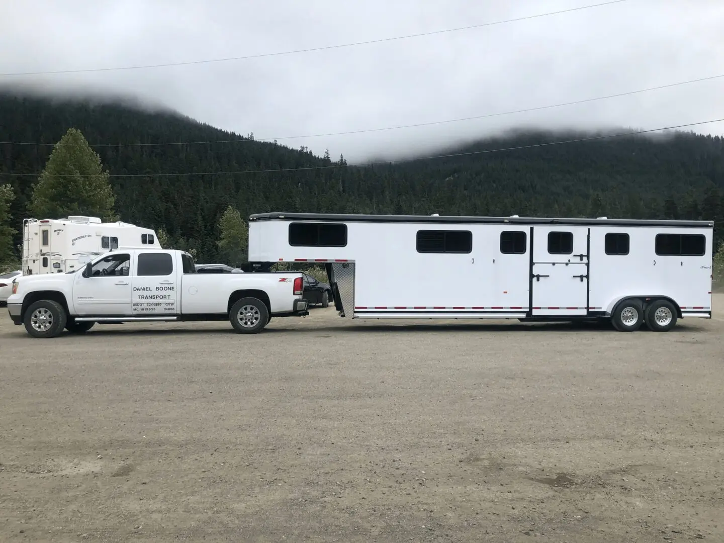 A truck and trailer with a horse in the back.