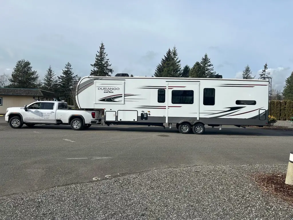 A truck pulling an rv on the road.