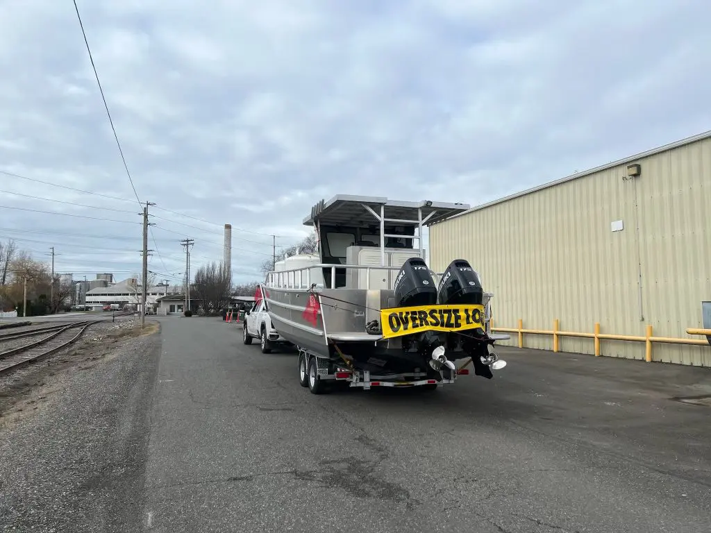 A large truck with two boats on the back of it.